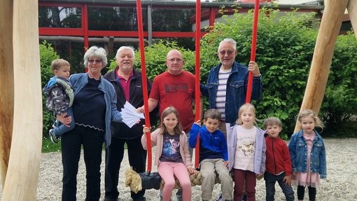 Foto: Stadt Friedrichsthal Die im Text erwähnten Personen stehen um eine massiver Holzschaukel herum. Geldumschläge werden überreicht. Kinder sitzen auf Schaukel.